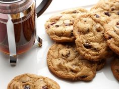 chocolate chip cookies and tea on a white plate next to a glass mug with cinnamon in it