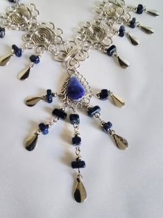 Beautiful Sodalite Necklace, consisting of 3 polished pieces of teardrop shaped sodalite, measuring 16mmx10mm, decorated with 4 white metal spirals linked with a metal wire butterfly shape, and finished with small pieces of sodalite and shiny white metal decorations.  This item is handmade and may have small imperfections.  Fitted with easy to use hook fastener. Handmade Silver Sodalite Necklaces, Handmade Silver Sodalite Necklace, Silver Sodalite Necklace With Natural Stones, Wire Butterfly, Metal Decorations, Silk Thread Earrings, Sodalite Necklace, Thread Earrings, Butterfly Shape