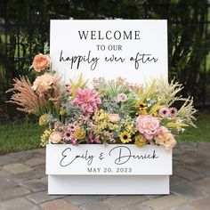 a welcome sign with flowers and greenery on it