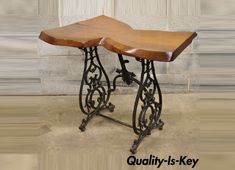 an antique sewing machine table with wooden top and iron legs, on display in front of a brick wall