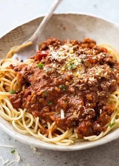 a white bowl filled with spaghetti and meat sauce