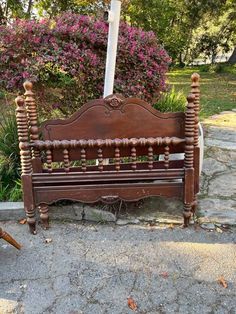 an old wooden bench sitting on the side of a road in front of some bushes