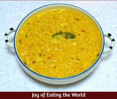 a white bowl filled with yellow soup on top of a table