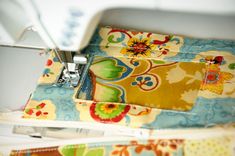 the sewing machine is next to some colorful fabric on the piece of cloth that has been sewn