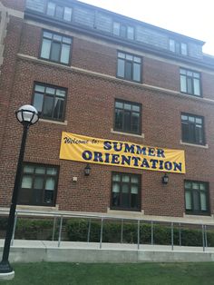 a large yellow sign on the side of a brick building that says summer orientation