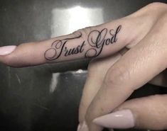 two hands with tattoos that say, trust god and have the same lettering on them