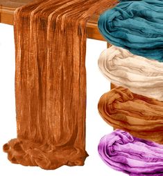 several different colored scarves sitting on top of a wooden table