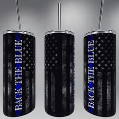 three black and blue american flag tumblers with straws in each one, on a gray background