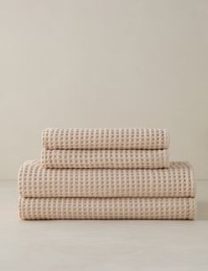 three folded sheets on top of each other, one in beige and the other in white