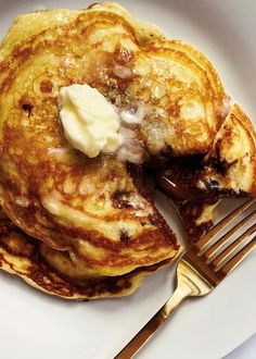 pancakes with butter and syrup are on a white plate next to a knife and fork