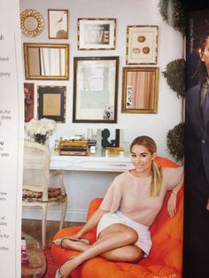 a woman sitting on top of an orange couch in a living room next to a coffee table