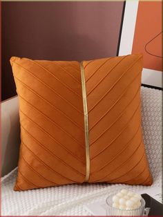 an orange pillow sitting on top of a bed