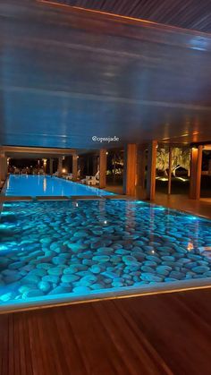 an indoor swimming pool is lit up with blue lights and pebbles on the bottom floor