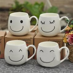 four coffee mugs with faces drawn on them are sitting in front of some boxes