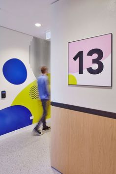 a man walking through an office lobby next to a colorful wall with numbers on it