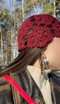 a woman with long hair wearing a red crochet headband and earring