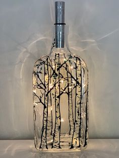 a glass bottle with lights in it and some trees on the inside is lit up