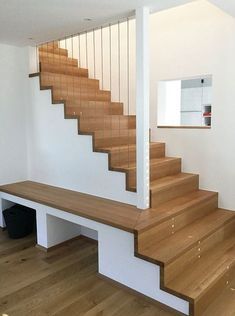 a wooden stair case next to a white wall and wood flooring in a house