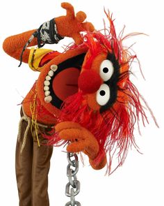 an orange stuffed animal with big eyes and long legs hanging from a metal chain on a white background