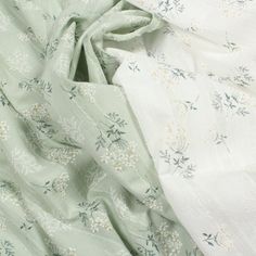 two white and green fabric with small flowers on the top one is folded up in half