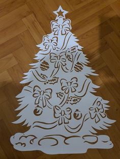 a paper cut christmas tree on a wooden floor