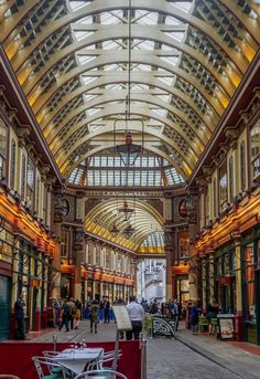 the inside of a building with many tables and chairs in front of it's glass roof