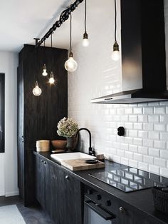 a black and white kitchen with lights hanging from the ceiling