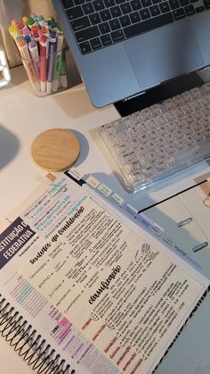 a laptop computer sitting on top of a desk next to a notebook and pen holder