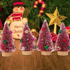 small christmas trees are lined up in front of a wooden table with ornaments and decorations