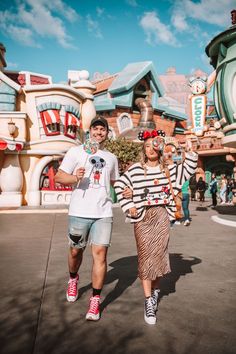 a man and woman are walking in front of a clock tower at disneyland's animal kingdom