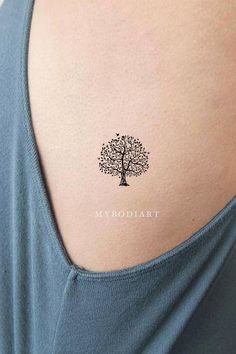 a small tree tattoo on the back of a woman's left shoulder, with the word