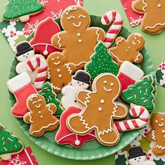 a plate full of decorated christmas cookies on top of a green table with red and white napkins