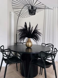 a black table with chairs and a vase on it in front of an umbrella shaped mirror