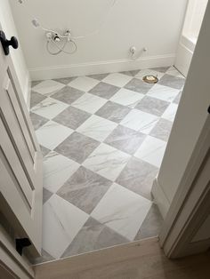 a bathroom with white and gray tile flooring next to a toilet in the corner