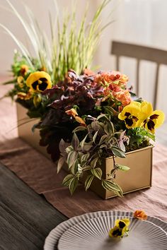 a table topped with plates and flowers on top of a wooden table