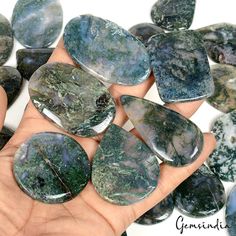 a hand is holding some green and white rocks