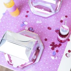 the table is set with pink and silver plates, confetti cups, and napkins