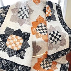 an orange and black quilt sitting on top of a chair