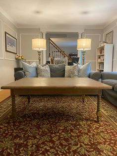 a living room with couches and a coffee table in front of a stair case