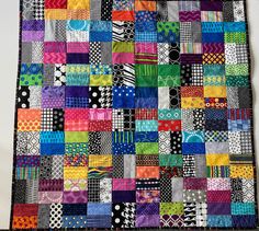 a multicolored patchwork quilt hanging on a wall