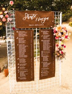 the seating chart for this wedding ceremony is displayed on a white metal stand with flowers