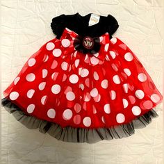 a red and black dress with white polka dots on the skirt is hanging on a wall