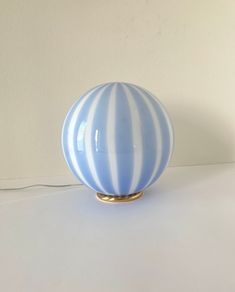 a blue and white striped vase sitting on top of a table next to a wall