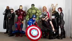 a group of people dressed up as superheros posing for a photo in front of a wall