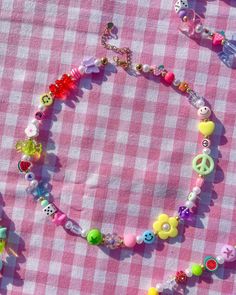 a pink and white checkered table cloth with beads, buttons and charms on it