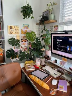 a desk with a computer monitor, keyboard and some plants