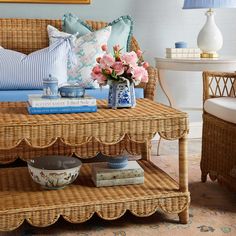 a wicker coffee table with flowers and books on it in front of a couch