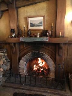 a fireplace with logs in it and a painting on the wall above it that is lit