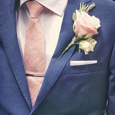 a man wearing a blue suit with a pink tie and flower boutonniere