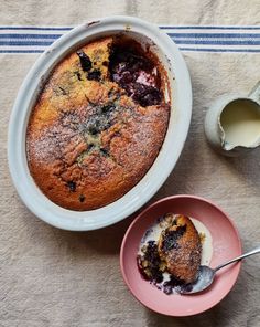 a blueberry cobbler in a white bowl next to a pink plate